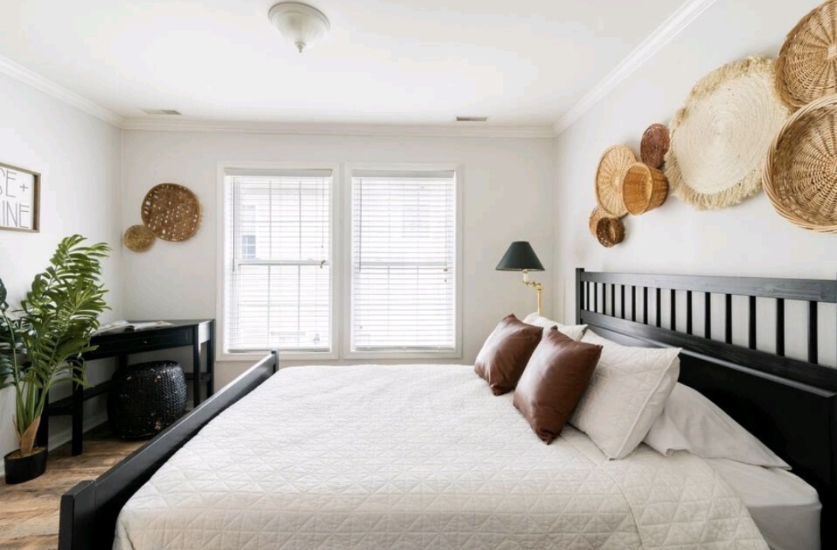 Bedroom with woven basket wall decor, black bed frame, and leather pillows