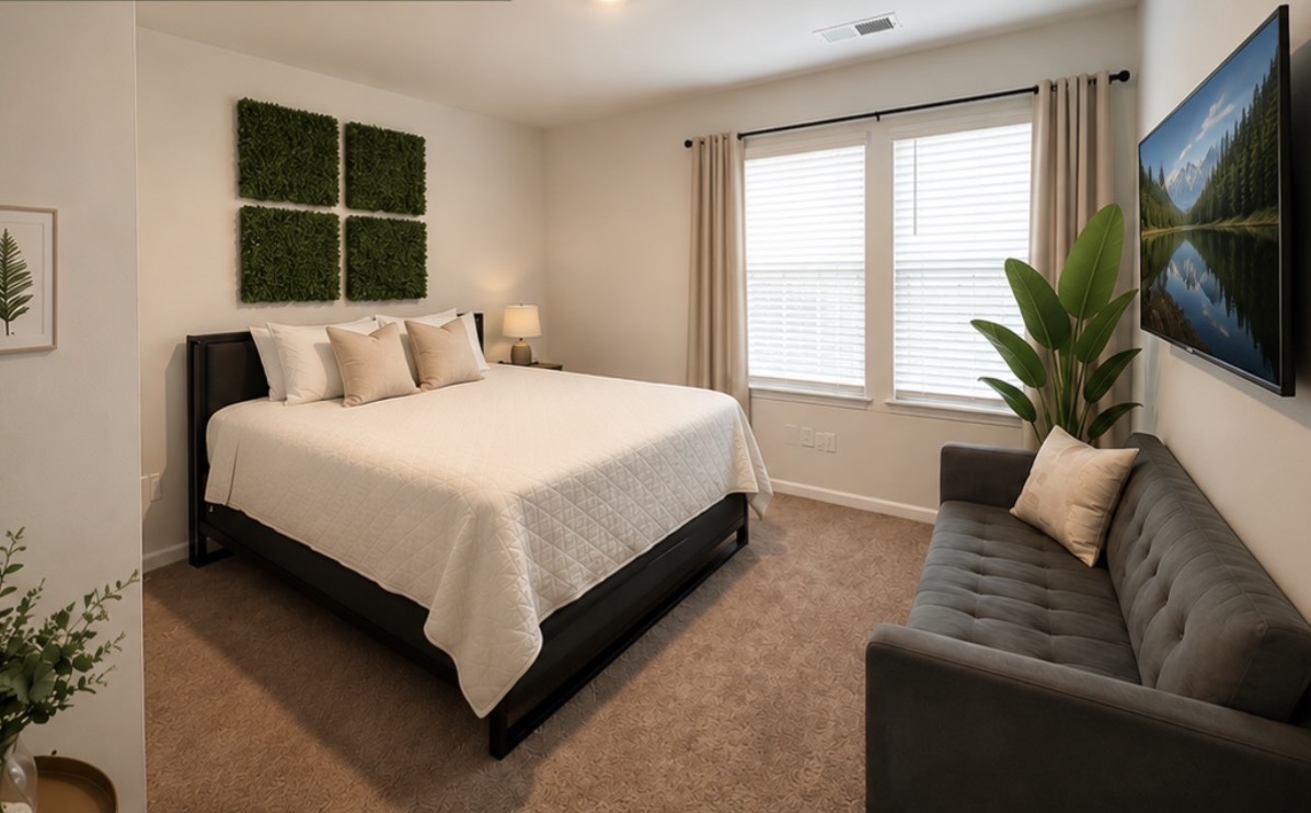 Furnished bedroom with greenery wall panels, tufted sofa, and natural light