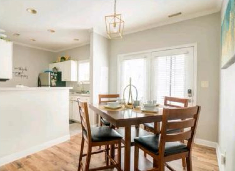 Dining area with wood table, pendant light, and kitchen beyond